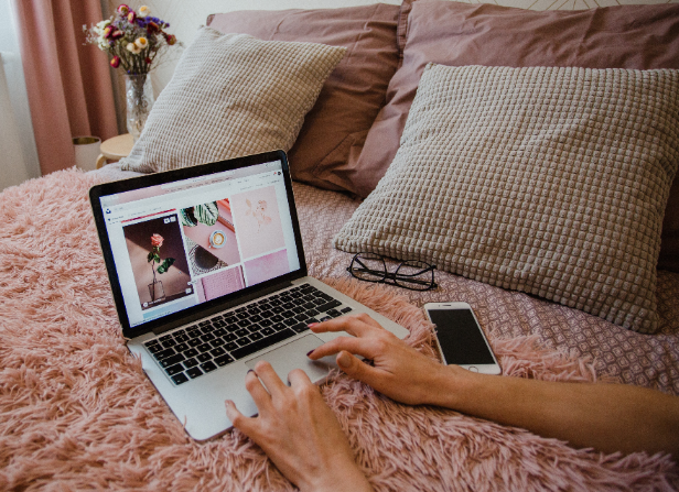 woman typing on laptop placed on bed